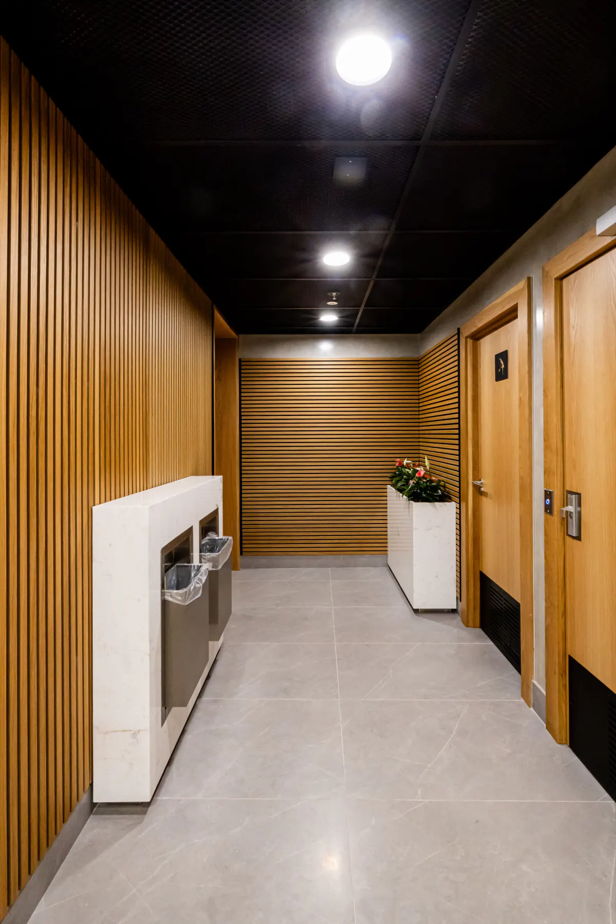 Corridor lined with vertical and horizontal natural wood-look slat walls