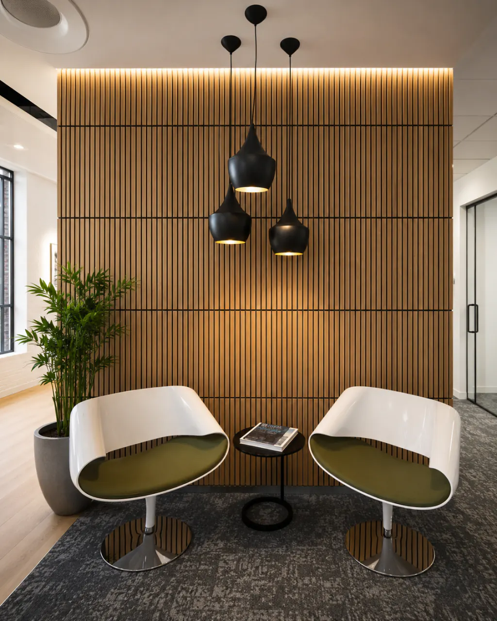 Office breakout area with a backlit natural wood-look slat wall behind two chairs