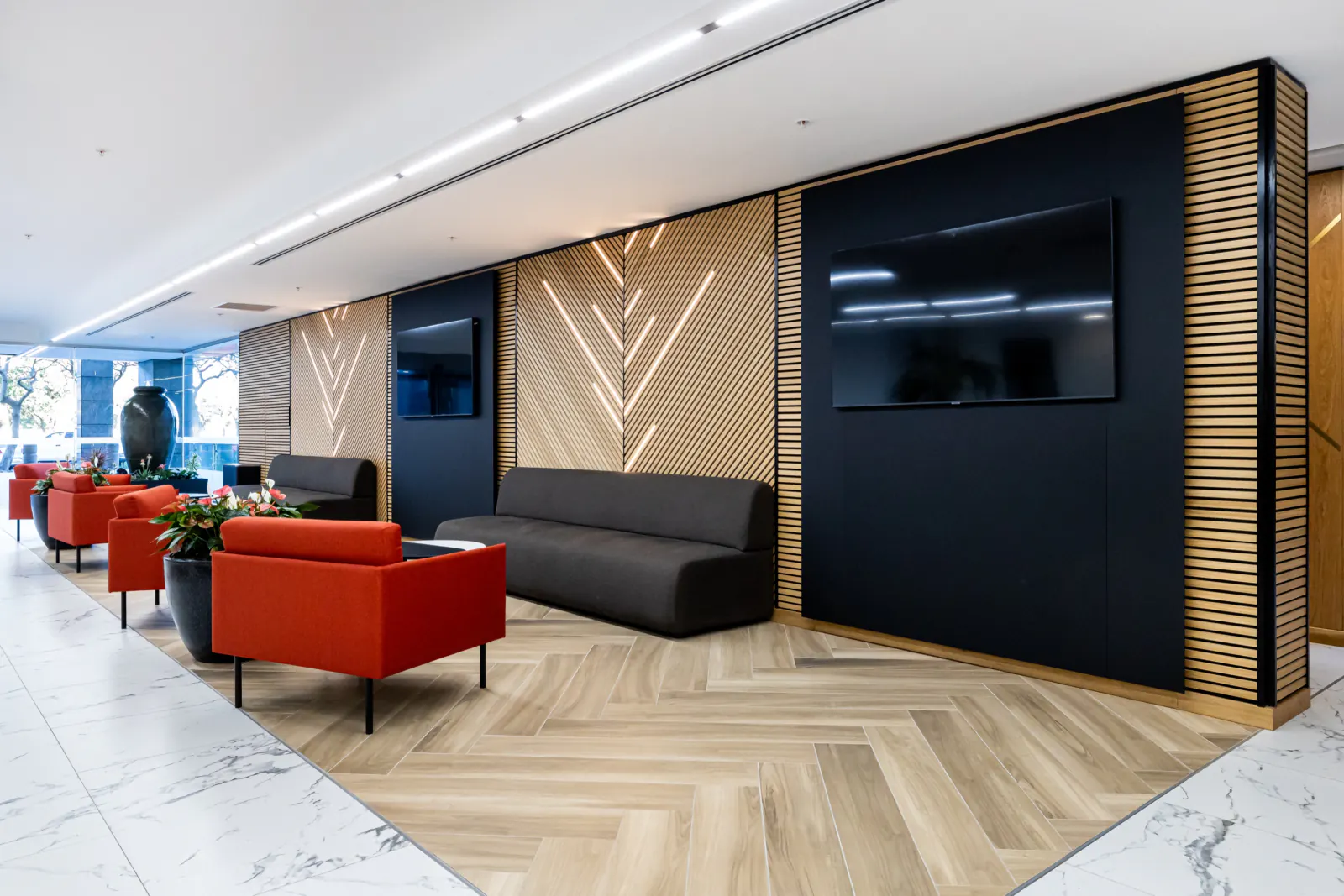 Office lobby with chevron and vertical natural wood-look slat wall panels behind the seating