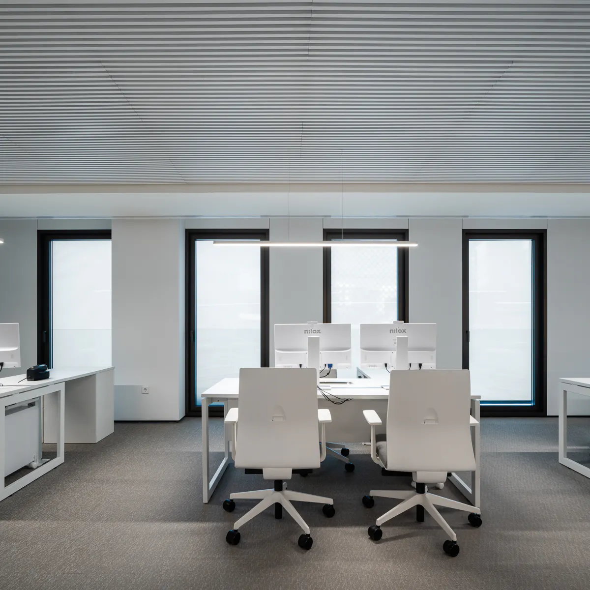 Office desks by the windows beneath a white slat ceiling